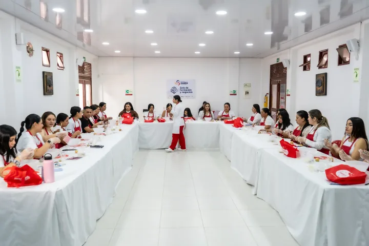 Participantes de una clase de Bakers Academy trabajando alrededor de una mesa.