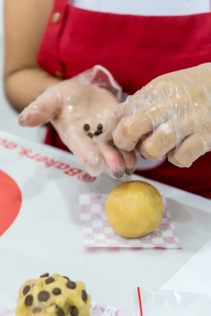 Manos formando porciones de masa durante una clase de cookies.